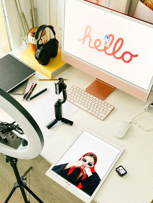 A sleek office desk setup featuring Apple devices: iMac, MacBook, and iPad.